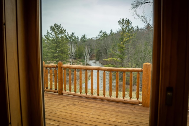 wooden terrace featuring a view of trees and a water view