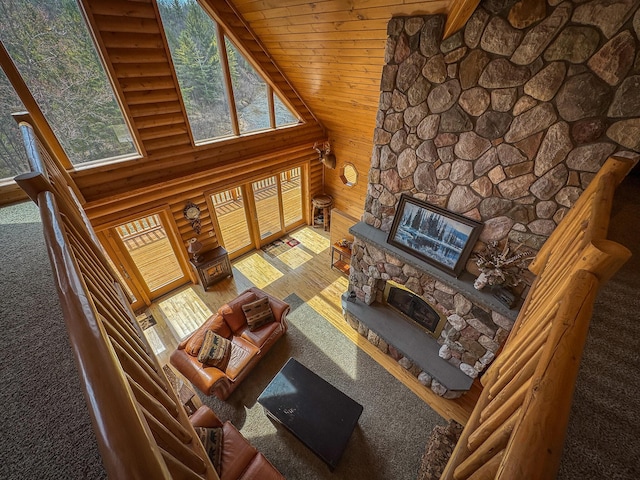 living area featuring a healthy amount of sunlight, a high ceiling, a fireplace, and wood finished floors