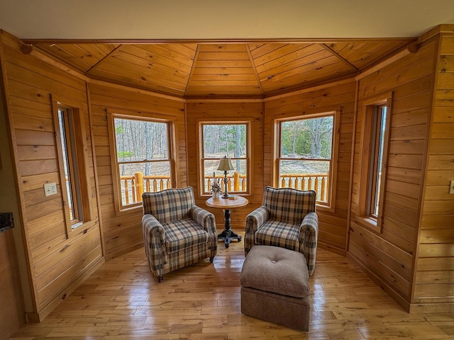 sitting room with wooden walls, light wood finished floors, wood ceiling, and lofted ceiling