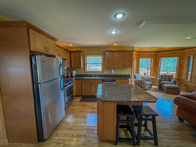 kitchen featuring light wood-type flooring, a sink, open floor plan, a breakfast bar, and stainless steel appliances