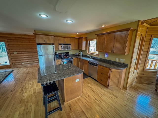 kitchen with a sink, appliances with stainless steel finishes, brown cabinetry, and light wood finished floors