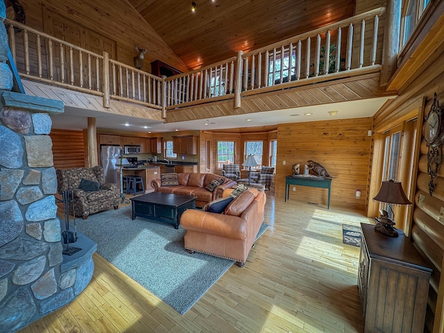 living area with wooden walls, high vaulted ceiling, wooden ceiling, and light wood-style flooring