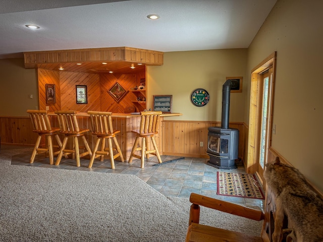 bar featuring wooden walls, a bar, and a wainscoted wall