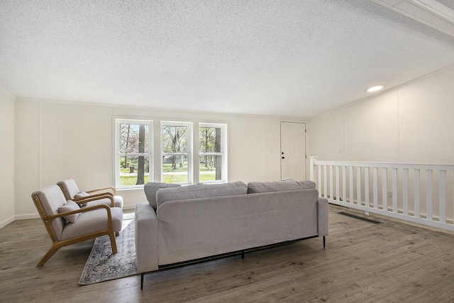 living area featuring a textured ceiling, lofted ceiling, and wood finished floors