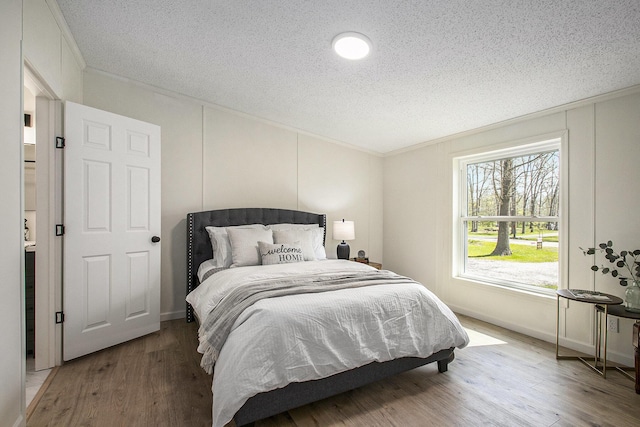 bedroom featuring crown molding, a textured ceiling, and wood finished floors