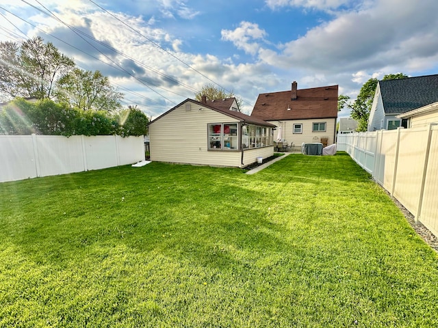 back of house featuring a yard, a sunroom, and a fenced backyard