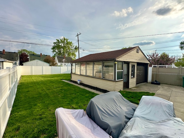 view of yard with concrete driveway, an outbuilding, a garage, and a fenced backyard