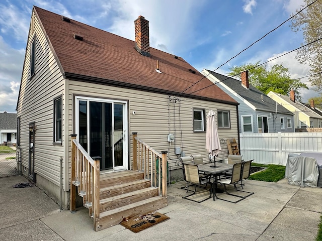 rear view of property featuring a chimney, fence, a patio, entry steps, and roof with shingles