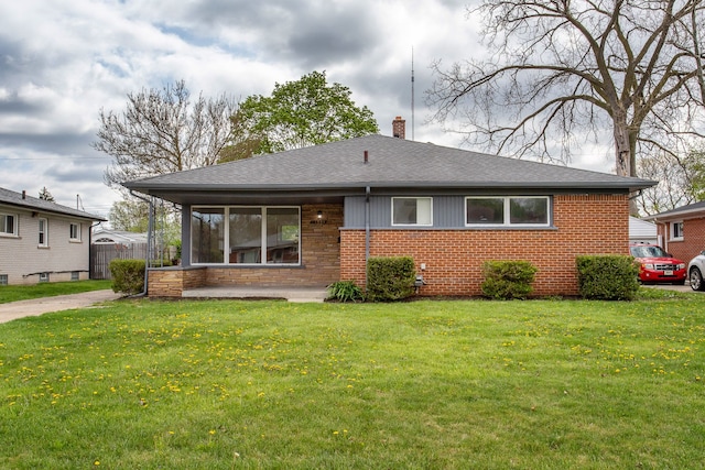 rear view of house featuring a lawn, brick siding, a chimney, and a shingled roof