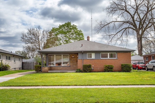 bungalow-style home featuring fence, a chimney, a front yard, and brick siding