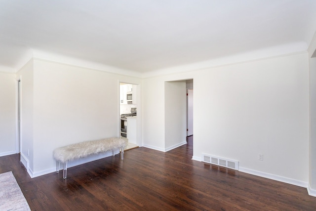 spare room featuring baseboards, dark wood-style flooring, and visible vents
