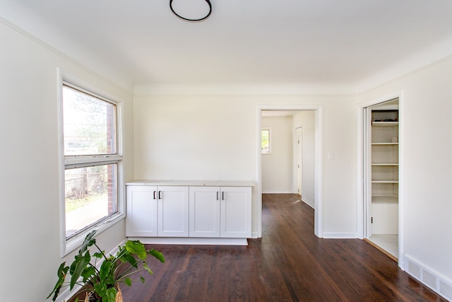 empty room featuring visible vents, dark wood finished floors, and baseboards