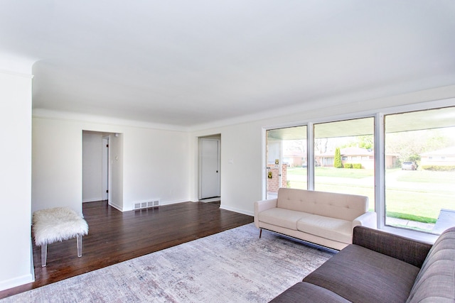 living area with visible vents, baseboards, and wood finished floors
