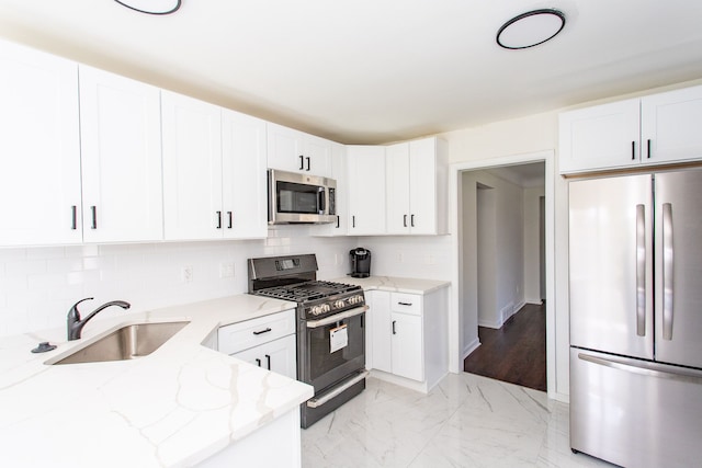 kitchen with decorative backsplash, light stone countertops, a sink, marble finish floor, and stainless steel appliances