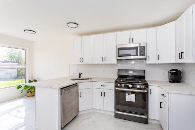 kitchen with marble finish floor, a peninsula, white cabinetry, and stainless steel appliances