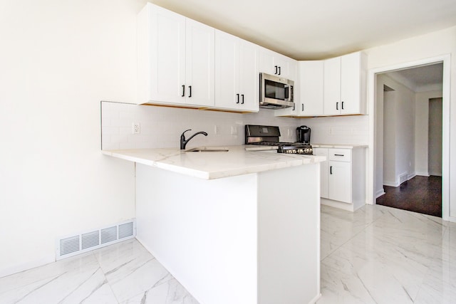 kitchen featuring light stone countertops, a sink, marble finish floor, stainless steel microwave, and range with gas cooktop