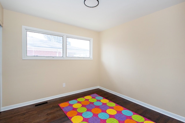 unfurnished room with baseboards, dark wood-style floors, and visible vents