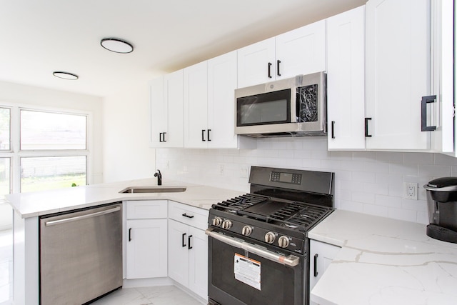 kitchen featuring white cabinets, a sink, marble finish floor, stainless steel appliances, and a peninsula