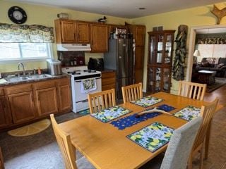 10100 Woodlawn Rd, Saint Helen, MI 48656 - kitchen featuring white electric range oven, a sink, freestanding refrigerator, brown cabinetry, and under cabinet range hood
