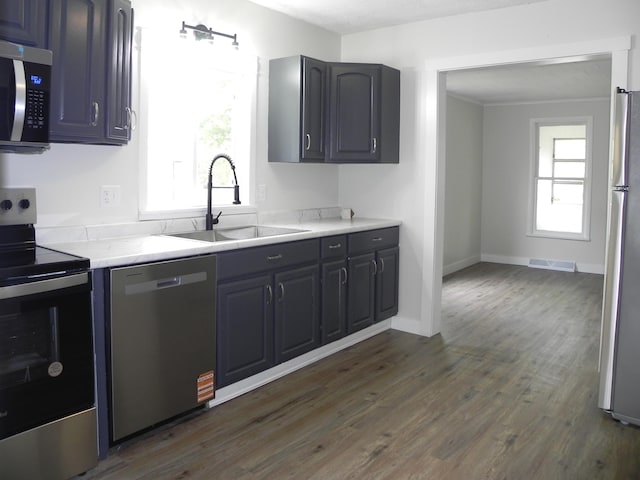 kitchen with dark wood-type flooring, a sink, appliances with stainless steel finishes, and light countertops