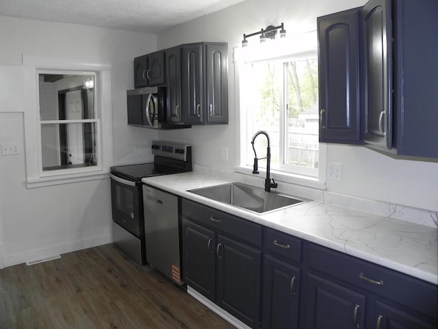 kitchen featuring blue cabinets, visible vents, a sink, stainless steel appliances, and dark wood-type flooring