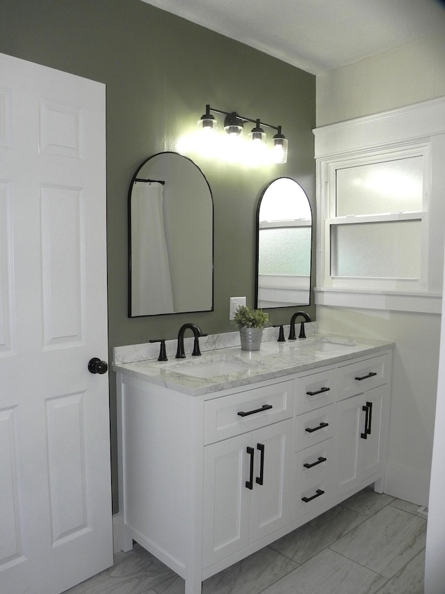 full bathroom featuring double vanity, a sink, and marble finish floor