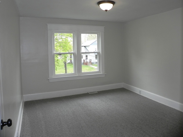 carpeted spare room with baseboards, visible vents, and a wealth of natural light