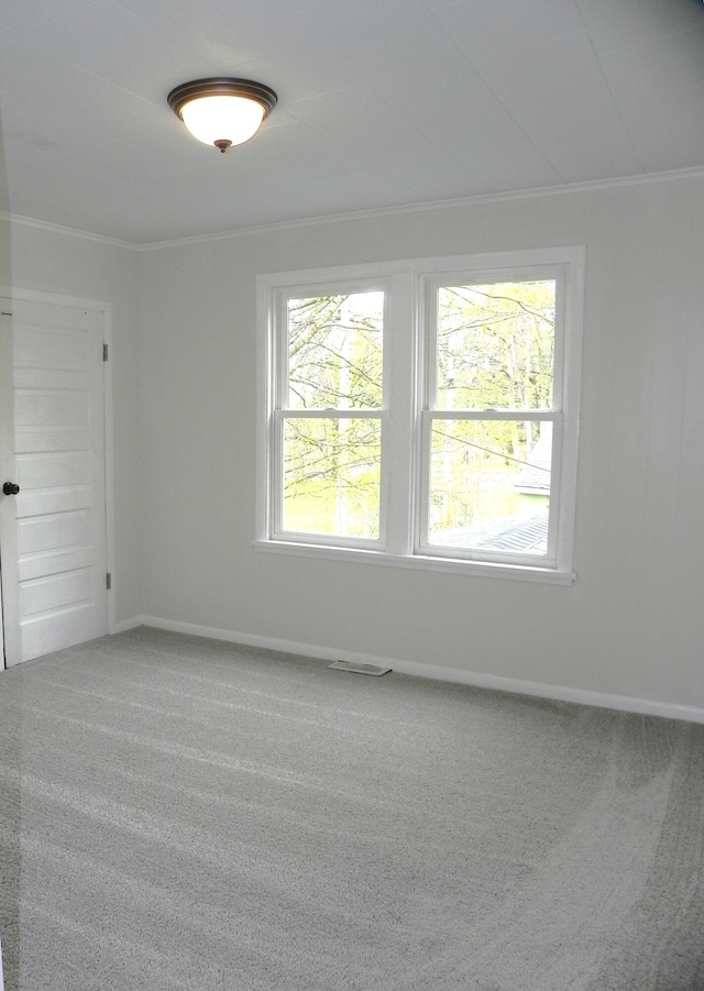 carpeted spare room featuring baseboards, ornamental molding, and visible vents