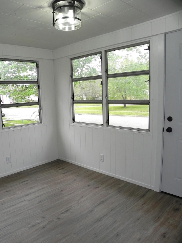 spare room featuring baseboards, wood finished floors, and a wealth of natural light
