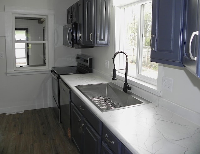 kitchen featuring visible vents, light stone countertops, range with electric stovetop, blue cabinets, and a sink