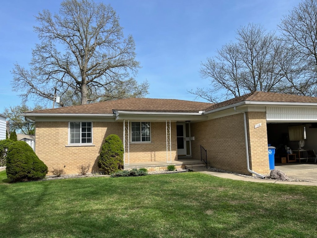 single story home featuring a front lawn, a porch, brick siding, and a garage
