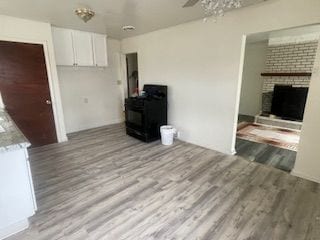 unfurnished living room with a fireplace, a ceiling fan, and wood finished floors