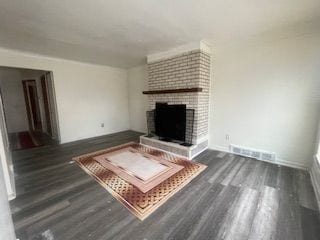 living room with baseboards, dark wood finished floors, visible vents, and a fireplace