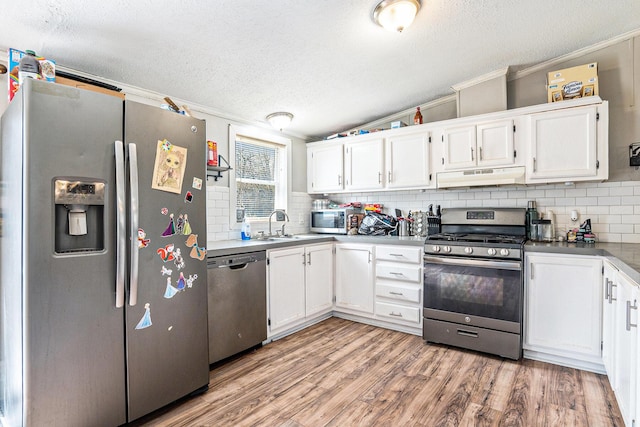 kitchen with crown molding, appliances with stainless steel finishes, under cabinet range hood, and a textured ceiling