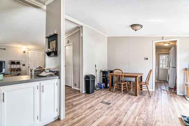 dining room with crown molding, washer / clothes dryer, light wood-style floors, and a textured ceiling