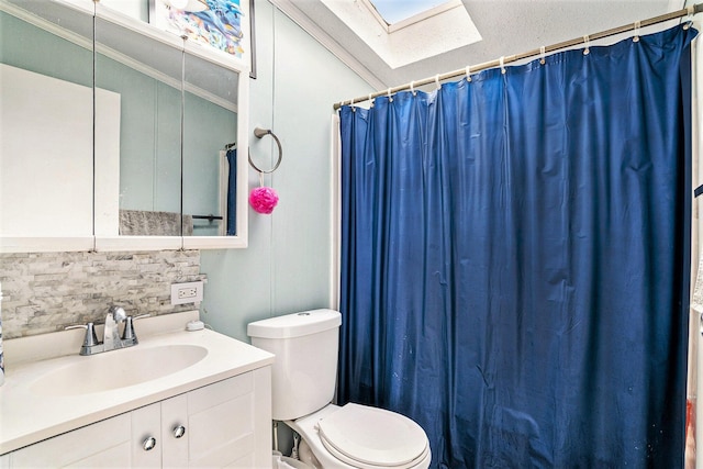 bathroom featuring vanity, toilet, decorative backsplash, a skylight, and ornamental molding