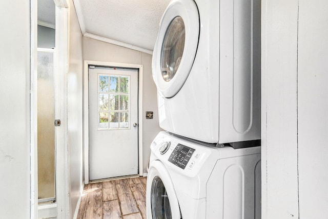 laundry area featuring laundry area, a textured ceiling, wood finished floors, ornamental molding, and stacked washer and clothes dryer