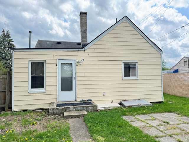 back of property with roof with shingles, fence, and a chimney