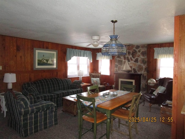 975 N Huron, East Tawas, MI 48730 - carpeted dining room with a ceiling fan, wood walls, a fireplace, and a textured ceiling