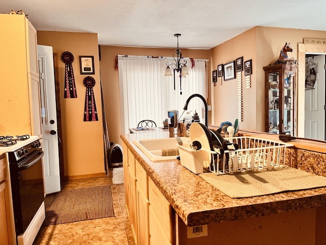 kitchen with range with gas cooktop, pendant lighting, light countertops, a sink, and an inviting chandelier