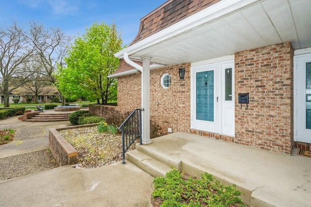 entrance to property featuring brick siding and mansard roof