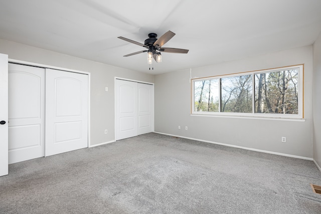 568 Foxboro Sq Unit 59, Brighton, MI 48116 - unfurnished bedroom featuring two closets, baseboards, carpet floors, and ceiling fan