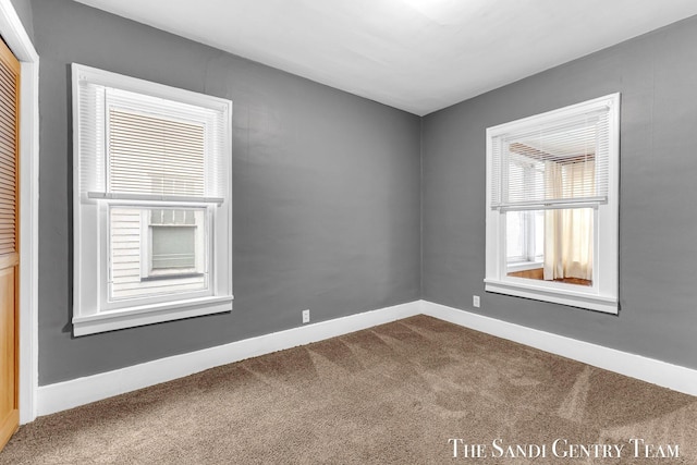 unfurnished room featuring baseboards and dark colored carpet