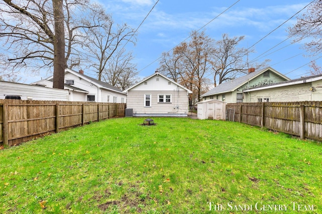 view of yard with a fenced backyard, an outbuilding, an outdoor fire pit, and a shed