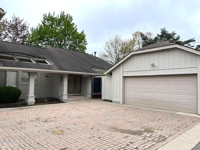 view of front facade with a shingled roof, decorative driveway, and a garage