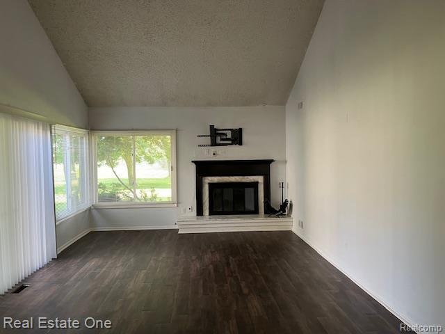 1797 Golf Ridge Dr, Bloomfield Hills, MI 48302 - unfurnished living room with lofted ceiling, a textured ceiling, dark wood-type flooring, and a high end fireplace