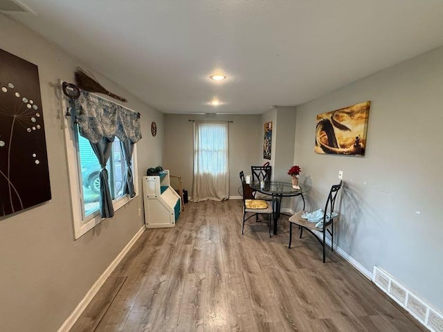 living area with baseboards, wood finished floors, and visible vents