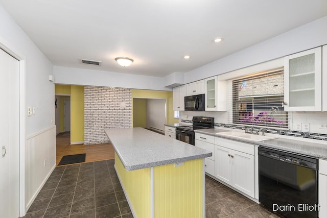 kitchen with visible vents, a kitchen island, dark tile patterned flooring, a sink, and black appliances