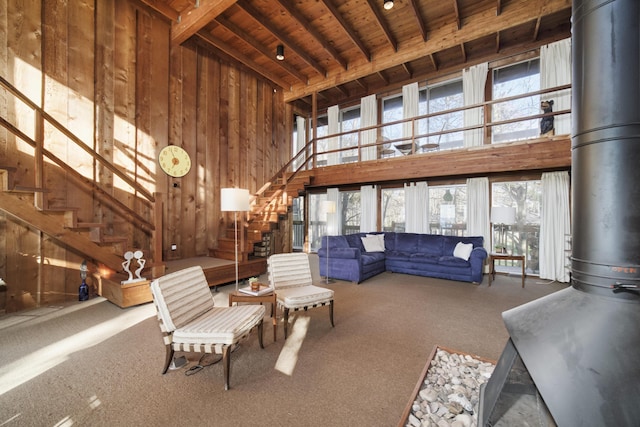 living room featuring a healthy amount of sunlight, wood ceiling, a wood stove, and carpet floors