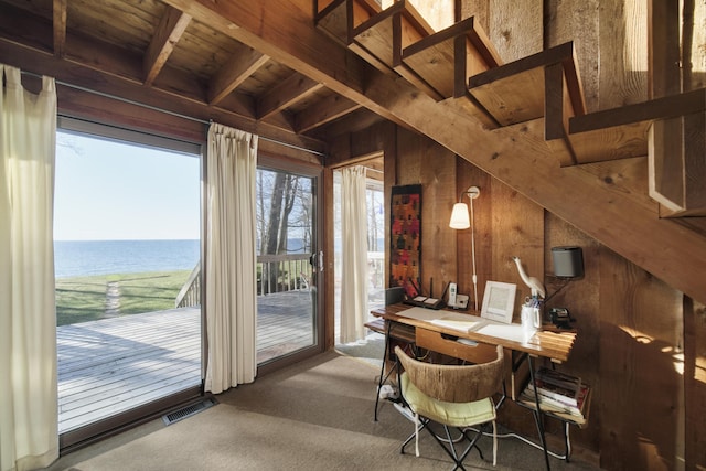 dining room featuring carpet floors, wood walls, beamed ceiling, wood ceiling, and a water view